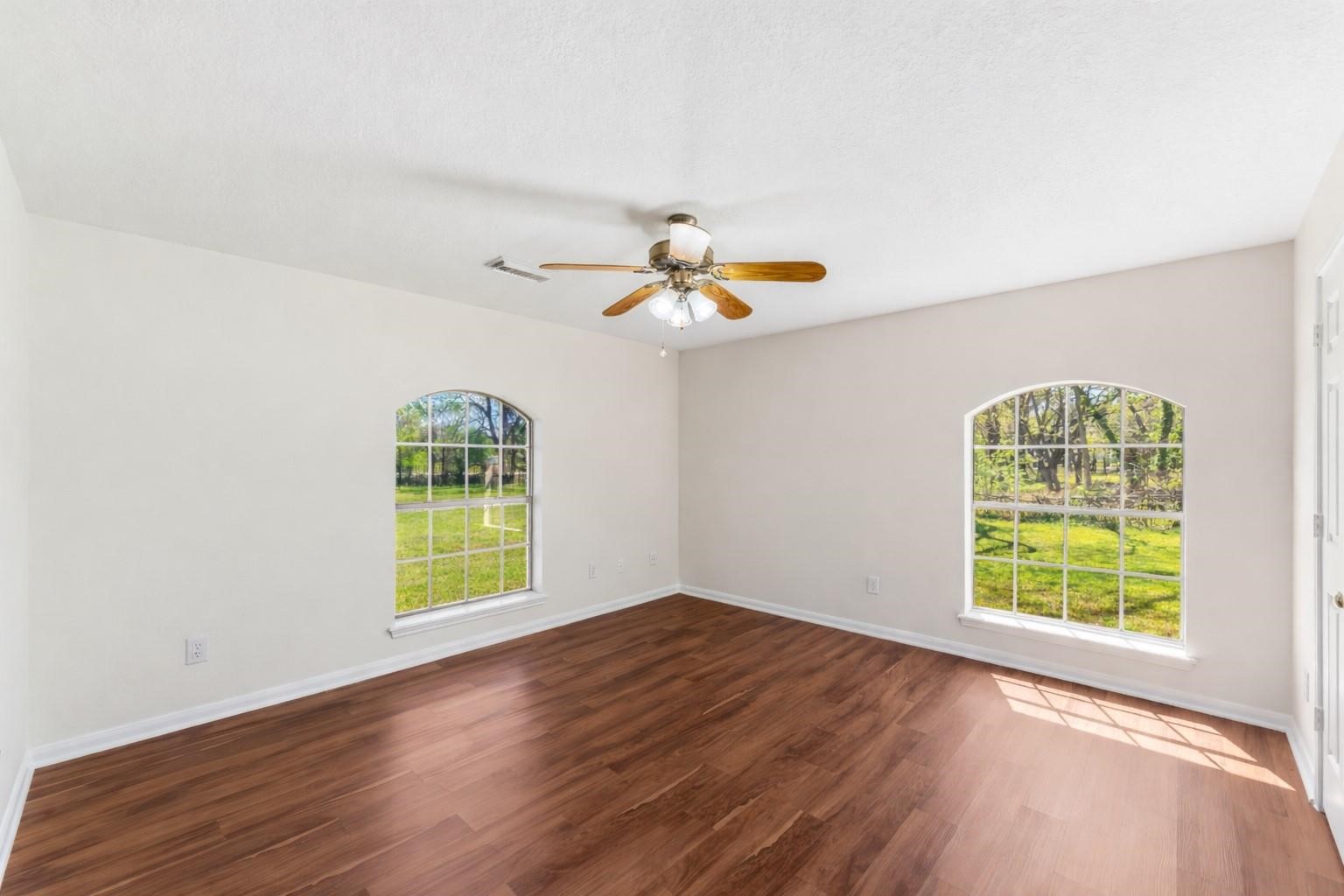 7825 Hughes Ranch Road Pearland, TX 77581 - Photo 17 of 28 Bright and welcoming with a lovely arched window and warm wood-look flooring, this secondary bedroom offers natural light, a comfortable layout, and a genuinely inviting feel.