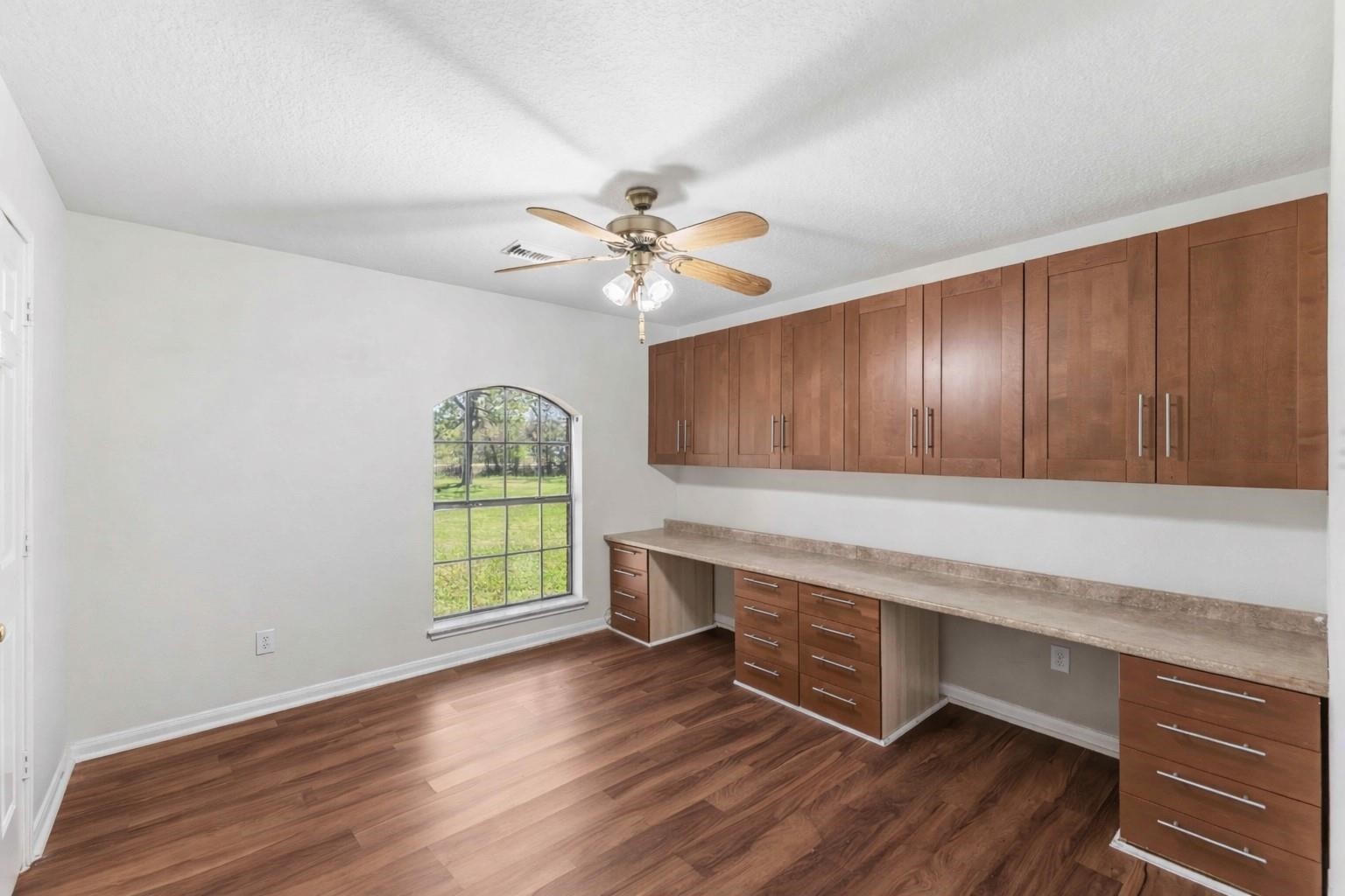 7825 Hughes Ranch Road Pearland, TX 77581 - Photo 19 of 28 A standout space with extensive built-in shelving and a dedicated desk area — ready to serve as a bedroom that doubles as a home office, study, or creative workspace without sacrificing comfort.