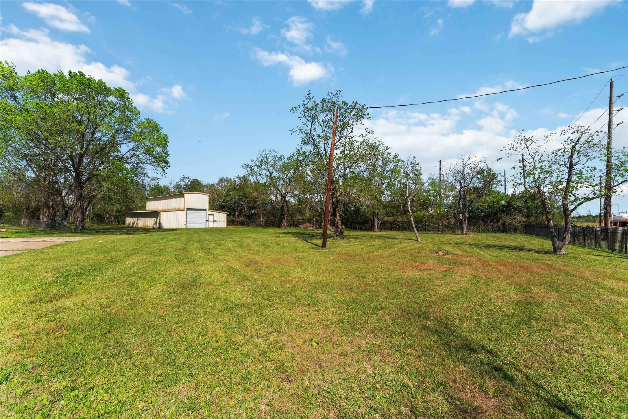 7825 Hughes Ranch Road Pearland, TX 77581 - Photo 25 of 28 Set against a backdrop of lush green grass and mature trees, this spacious metal building and its surrounding open grounds paint a picture of true country living — plenty of room to roam.
