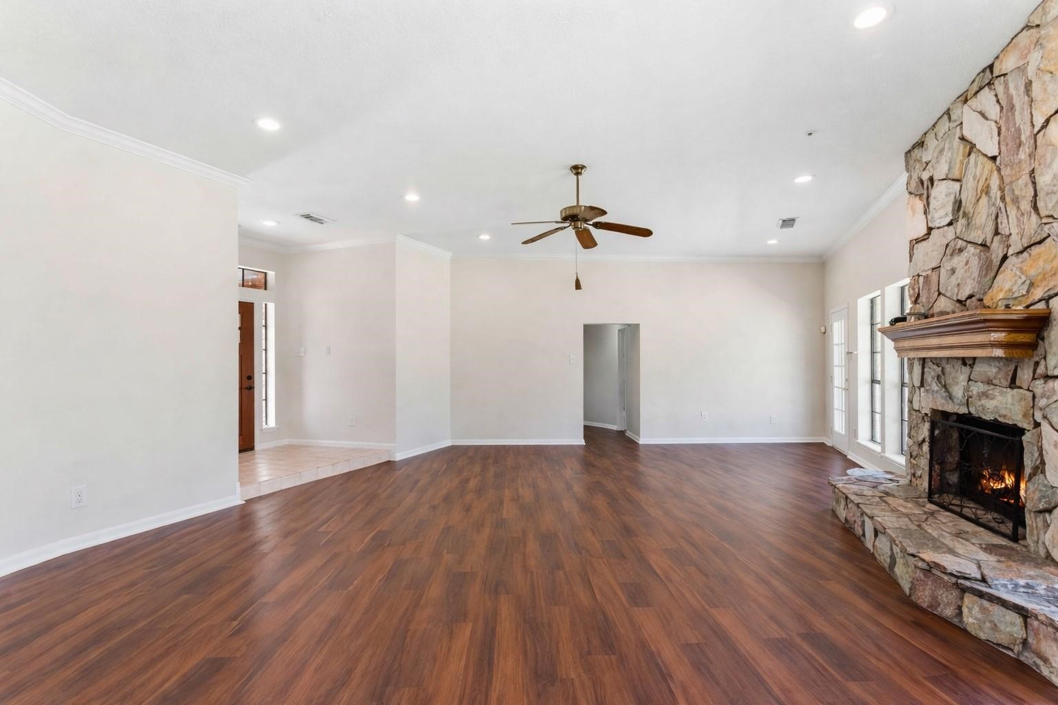 7825 Hughes Ranch Road Pearland, TX 77581 - Photo 6 of 28 The stone fireplace anchors the living room with undeniable presence, while expansive windows frame the beautiful outdoor surroundings. Rich wood-look flooring and soaring ceilings complete the picture.