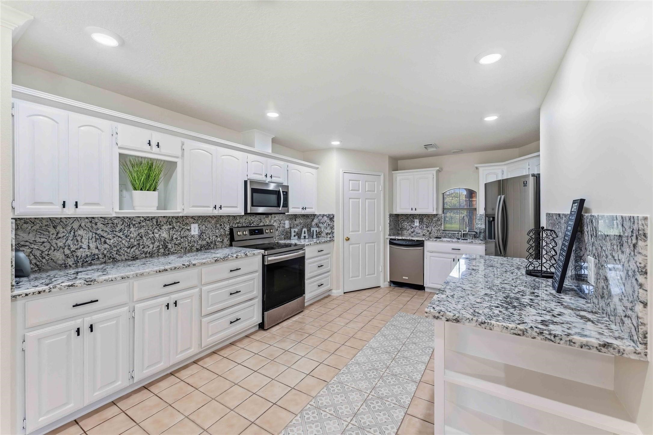 7825 Hughes Ranch Road Pearland, TX 77581 - Photo 8 of 28 Freshly updated and move-in ready — new granite countertops, new granite backsplash, and freshly painted cabinetry bring a clean, polished look to this bright and functional kitchen.