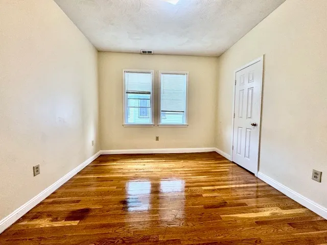 a view of an empty room with window and wooden floor