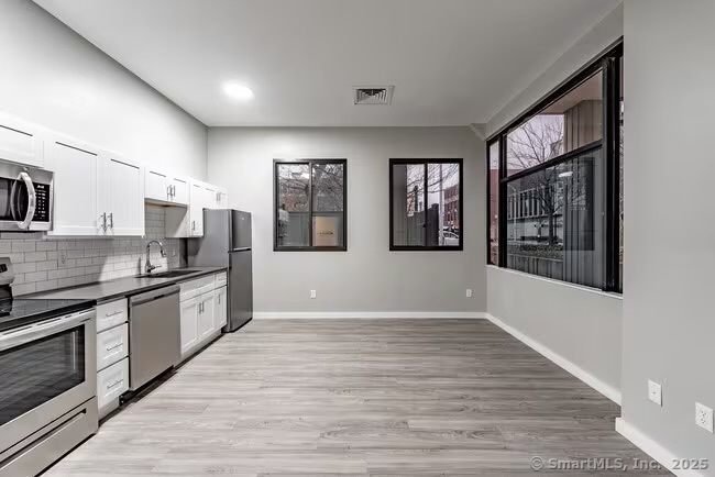 333 State Street, Unit 705 Bridgeport, CT 06604 - Photo 4 of 18 a large kitchen with stainless steel appliances granite countertop a large stove top oven and cabinets