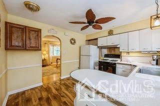 237 Amboy Road Old Bridge, NJ 07747 - Photo 14 of 39 a kitchen with stainless steel appliances a stove a refrigerator a sink a dining table and chairs with wooden floor