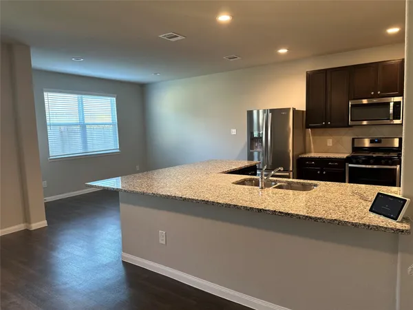 a view of a kitchen with kitchen island a sink appliances and a counter top space