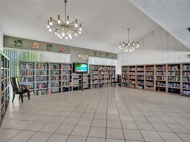 a room with a chair and white cabinets with wooden floor