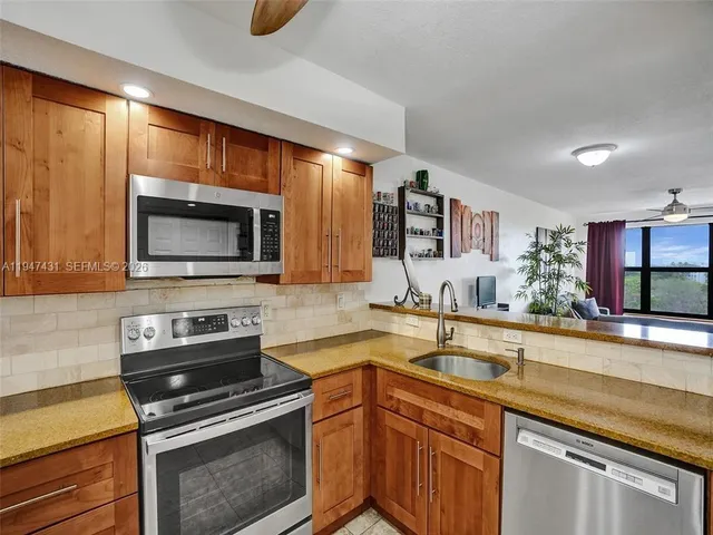a kitchen with stainless steel appliances granite countertop a sink a stove and cabinets