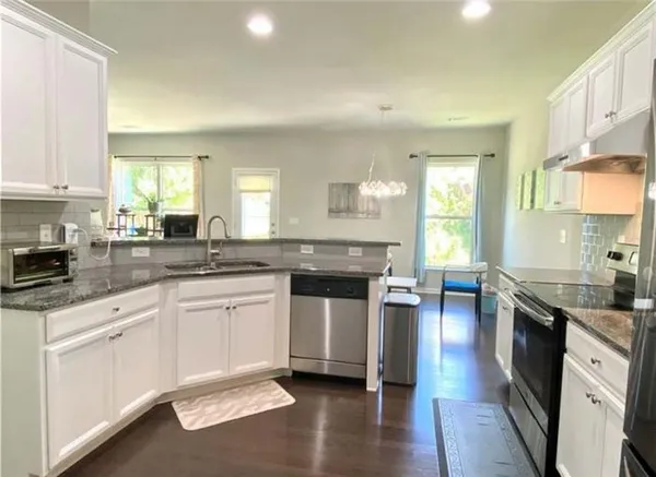 a kitchen with stainless steel appliances granite countertop a stove a sink dishwasher and a microwave oven with white cabinets