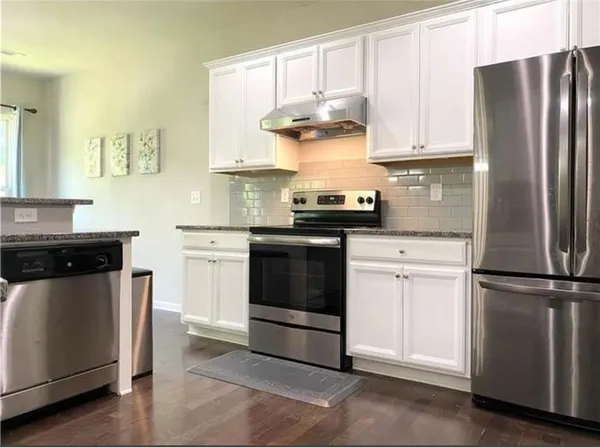 a kitchen with stainless steel appliances granite countertop white cabinets a refrigerator a sink and a stove