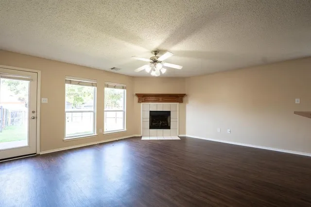 an empty room with wooden floor fireplace and windows