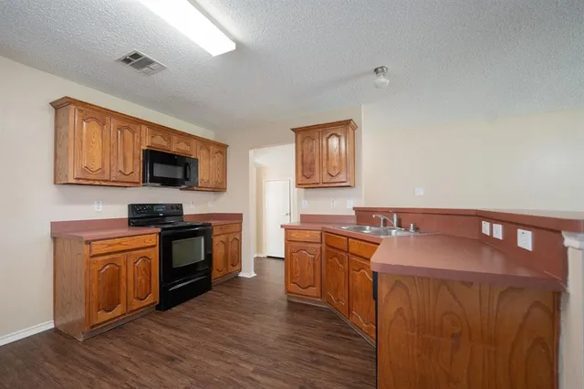 a kitchen with stainless steel appliances granite countertop a stove top oven a sink dishwasher a microwave oven with granite countertops and cabinets