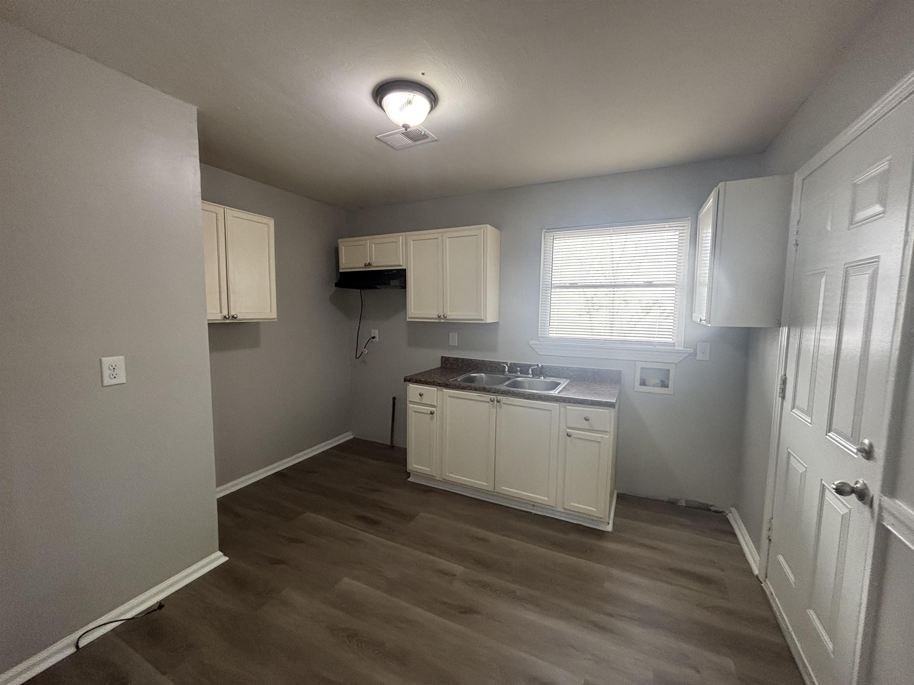2591 Callie Road Memphis, TN 38127 - Photo 7 of 13 Kitchen area featuring light gray walls, wood-finish flooring, white cabinetry, and a double basin sink with a window overhead