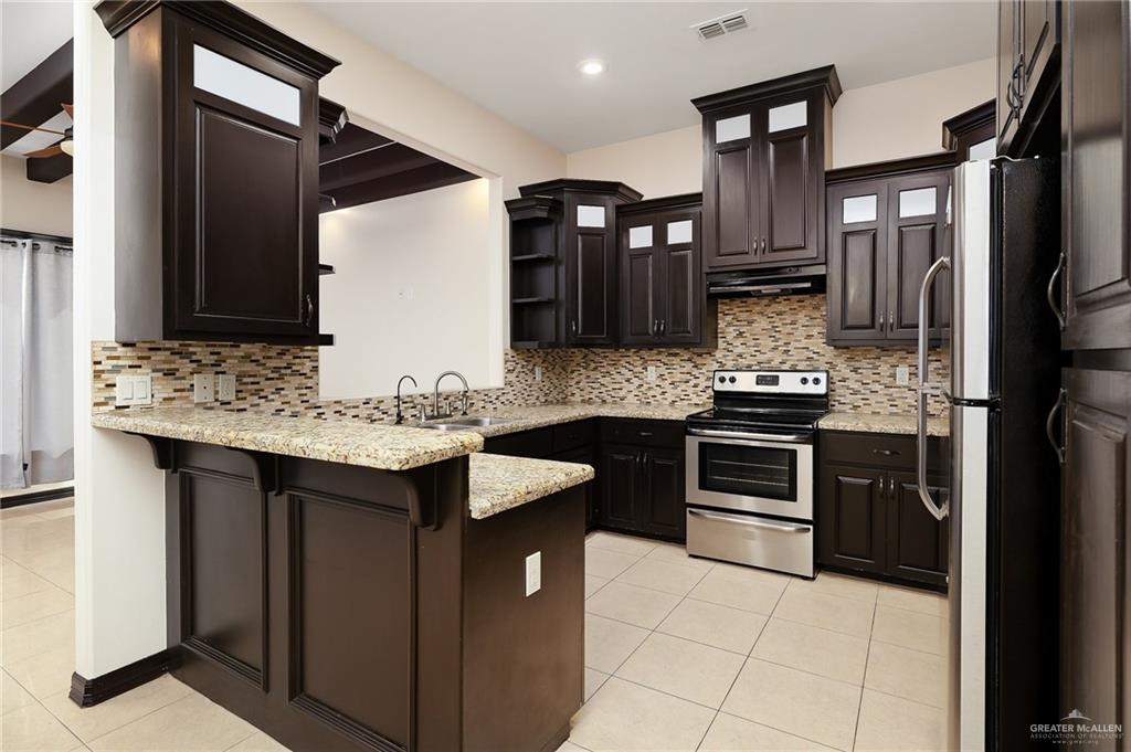 7027 North 3rd Street, Unit 7027 McAllen, TX 78504 - Photo 6 of 14 a kitchen with stainless steel appliances kitchen island granite countertop a sink stove and refrigerator