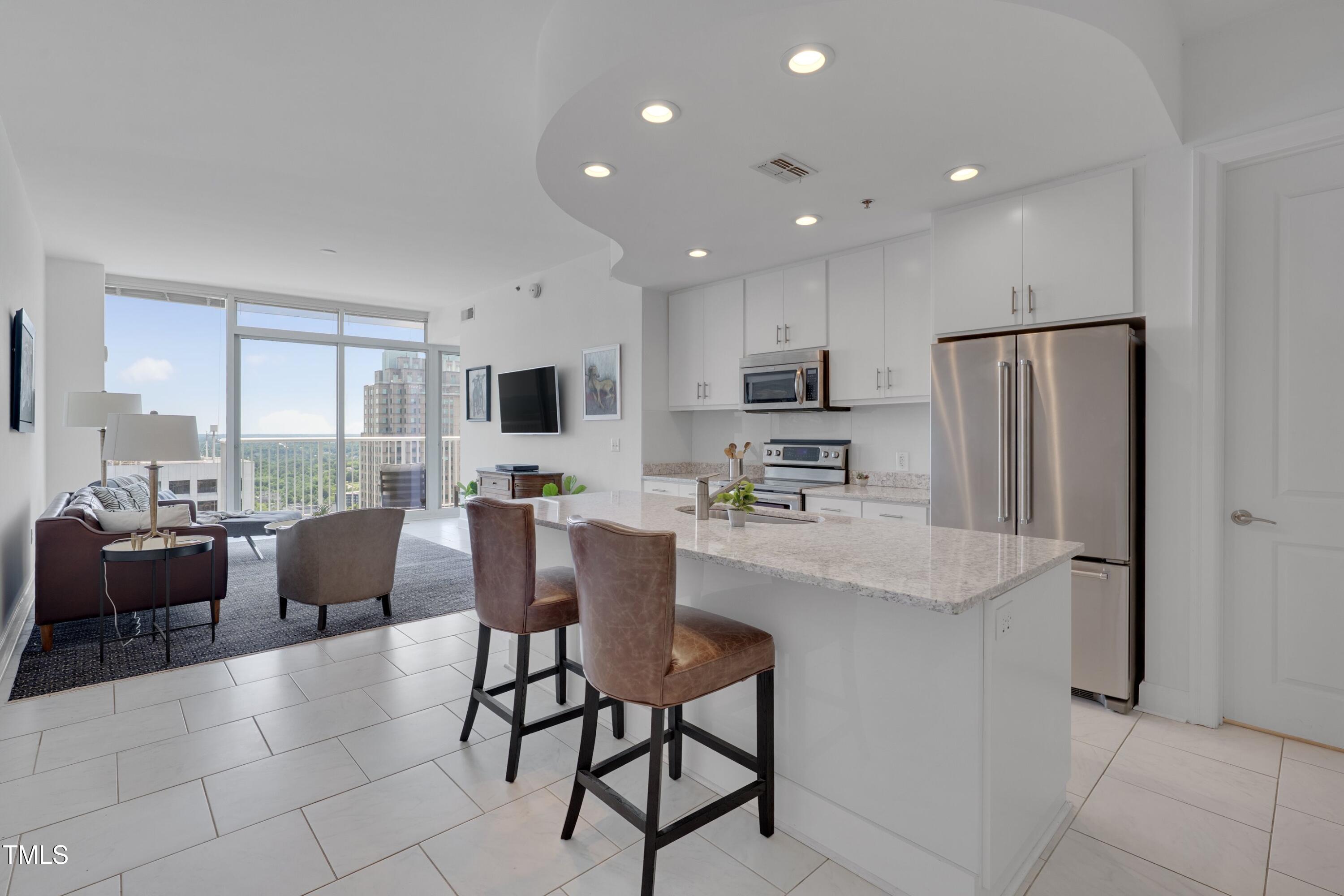 a kitchen with stainless steel appliances kitchen island granite countertop a refrigerator and a stove top oven with white cabinets