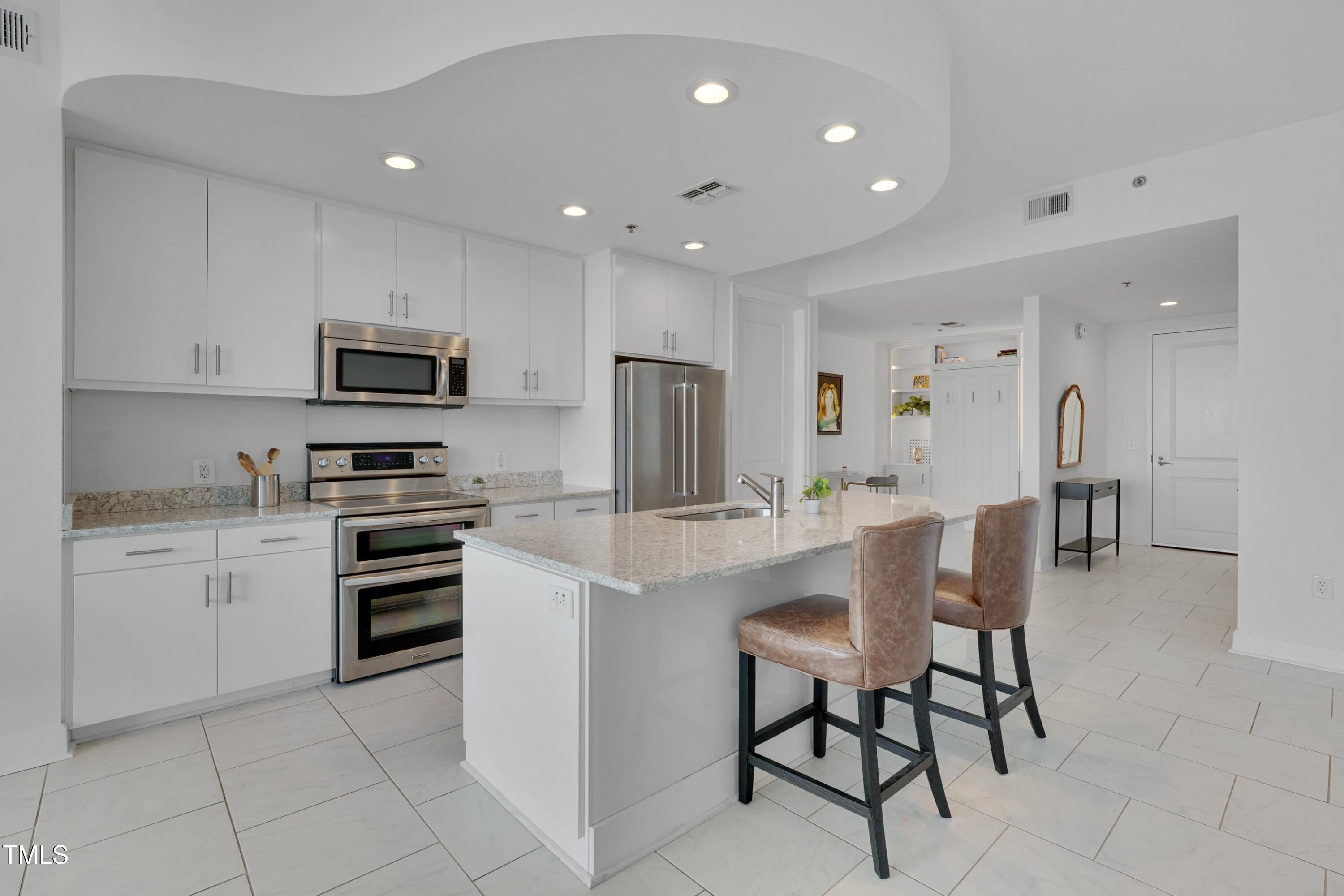 301 Fayetteville Street, Unit 2611 Raleigh, NC 27601 - Photo 2 of 44 a kitchen with stainless steel appliances a stove a sink a refrigerator and a dining table