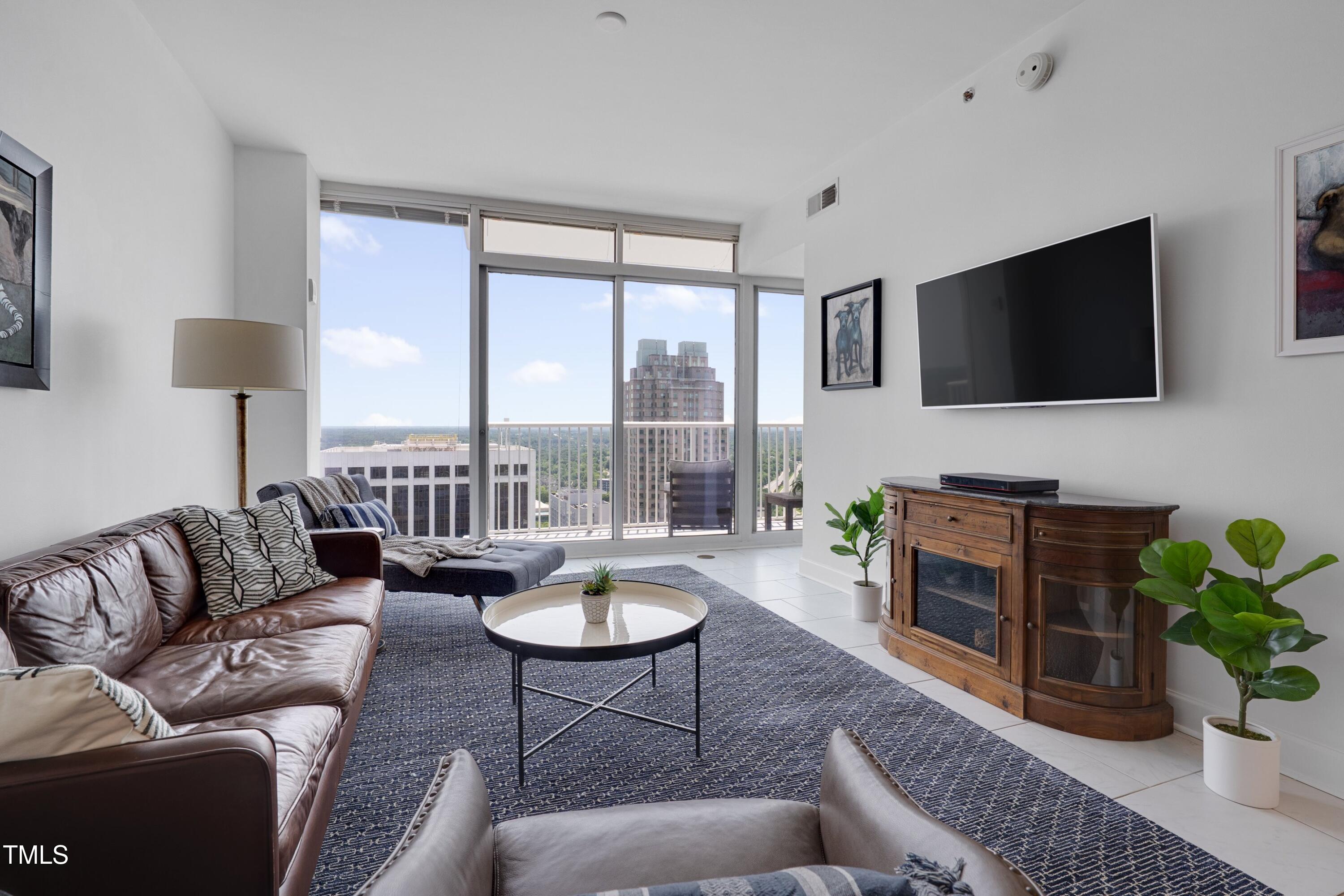 301 Fayetteville Street, Unit 2611 Raleigh, NC 27601 - Photo 3 of 44 a living room with furniture a flat screen tv and a floor to ceiling window