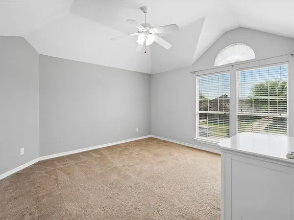 an empty room with chandelier fan and windows