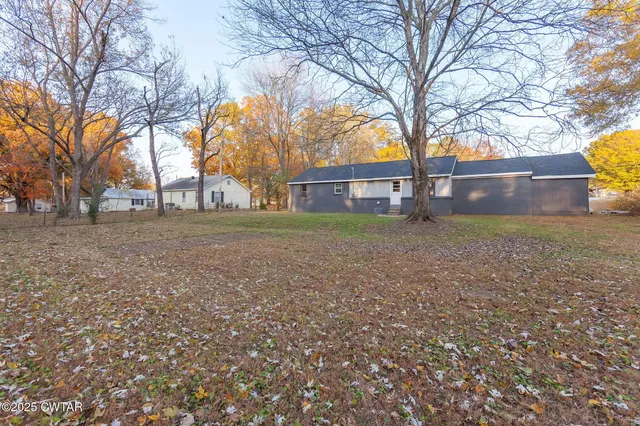 a backyard of a house with large trees and outdoor seating
