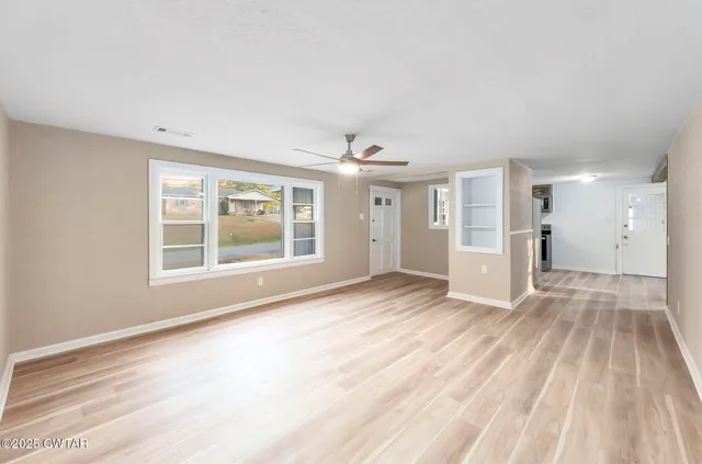 a view of empty room with wooden floor and windows