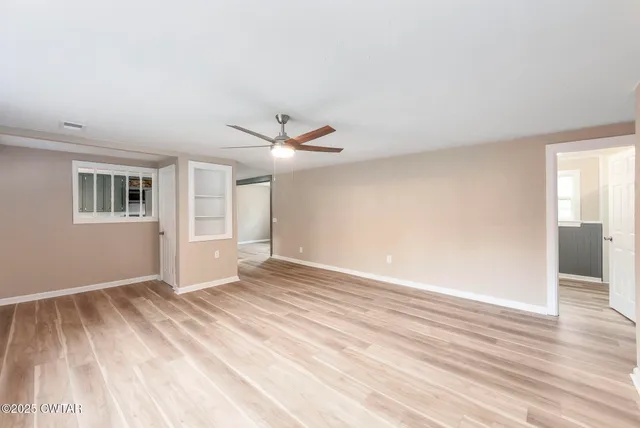a view of an empty room with wooden floor and a window