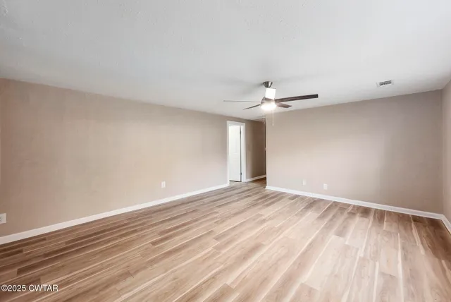 a view of an empty room with wooden floor
