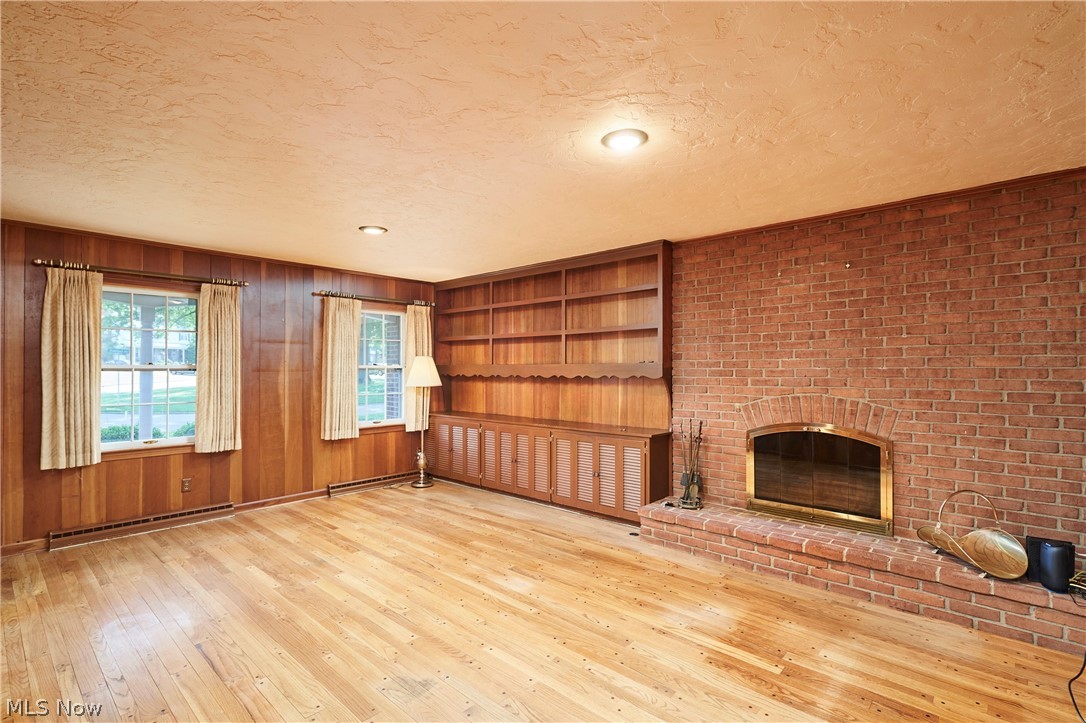 354 Tremont Road Akron, OH 44313 - Photo 14 of 34 Hardwood flooring throughout featuring brick fireplace, built-in shelving, wood paneling, and two double-hung windows
