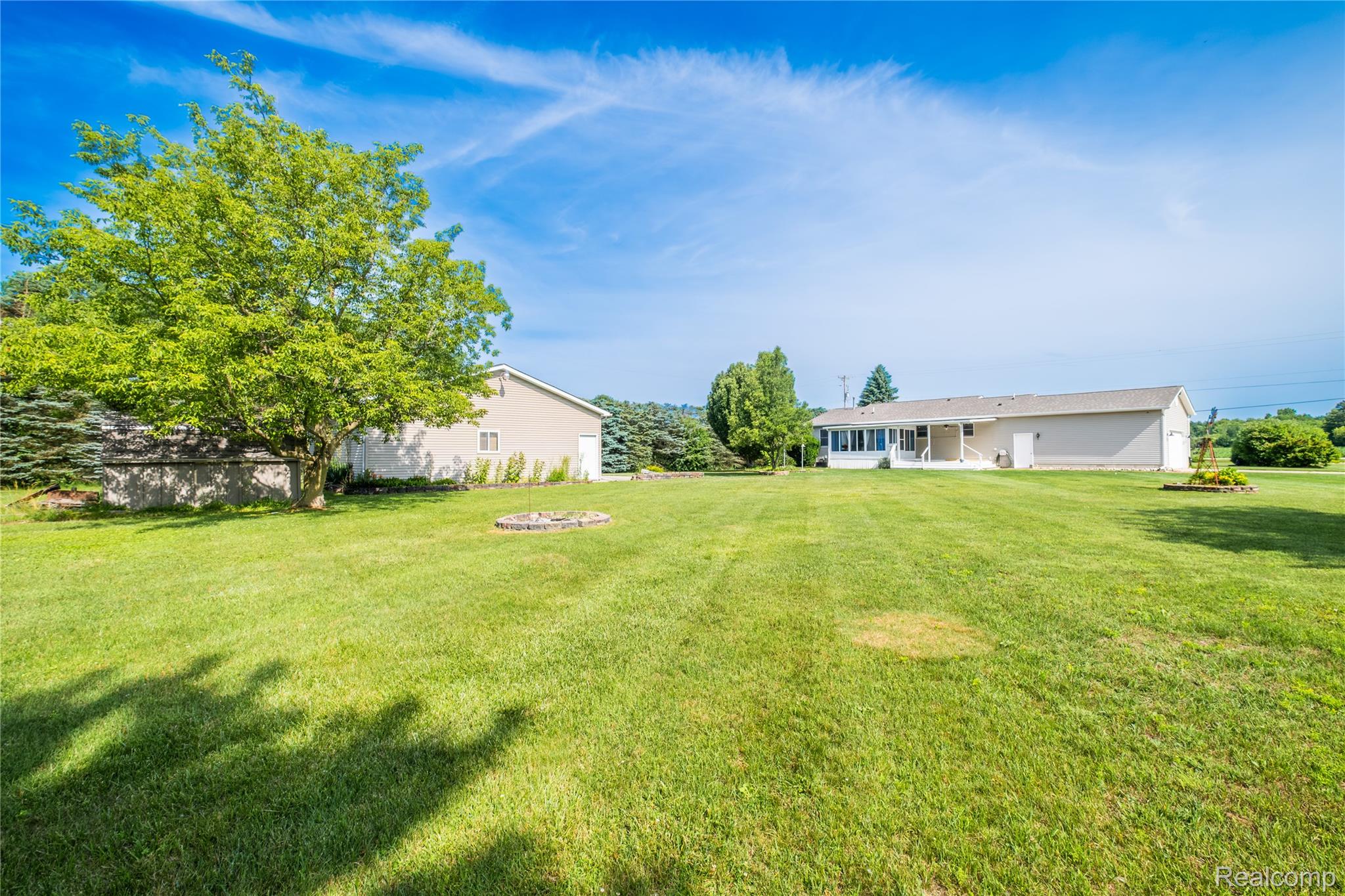 9600 Hamill Road Otisville, MI 48463 - Photo 29 of 32 Spacious green lawn with mature trees and a circular stone fire pit