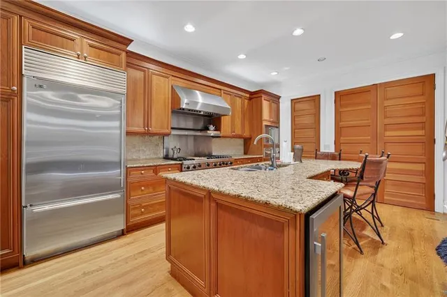 a kitchen with stainless steel appliances granite countertop a kitchen island a stove a sink and a refrigerator