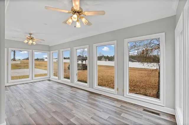 an empty room with wooden floor and a ceiling fan
