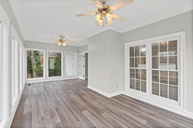 a view of an empty room with wooden floor and a window