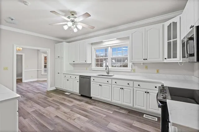 a kitchen with granite countertop a stove a sink and dishwasher with white cabinets