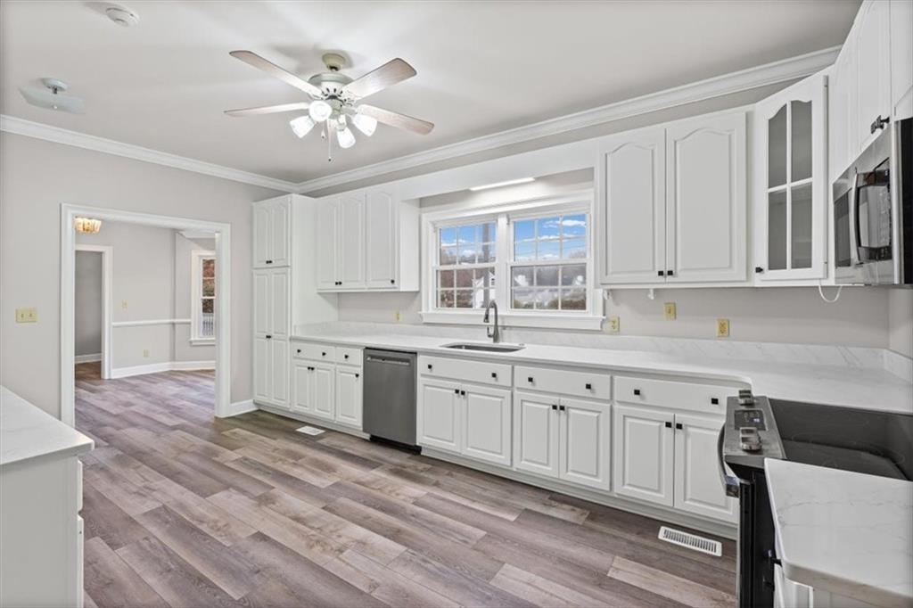 4003 Garden Lakes Parkway Rome, GA 30165 - Photo 6 of 20 a kitchen with granite countertop a stove a sink and dishwasher with white cabinets