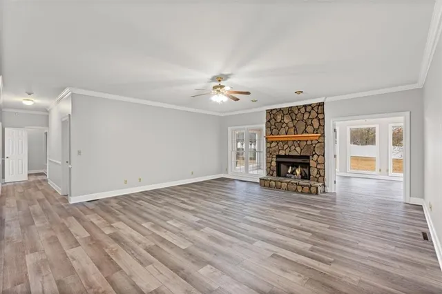 wooden floor in an empty room with a fireplace and a window