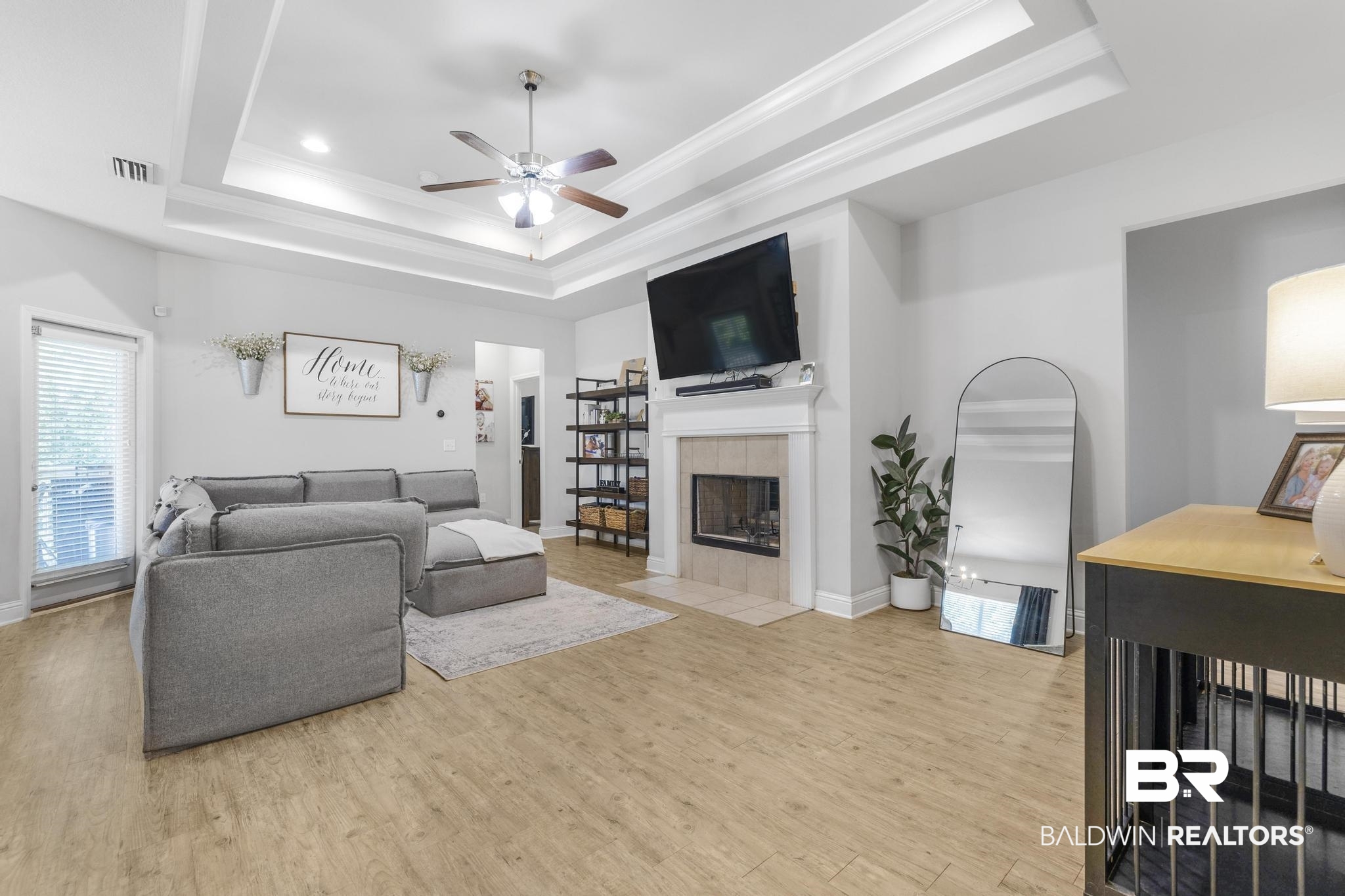 31336 Hoot Owl Road Daphne, AL 36527 - Photo 2 of 36 Living area with a tile fireplace, light wood finished floors, ornamental molding, a raised ceiling, and a ceiling fan