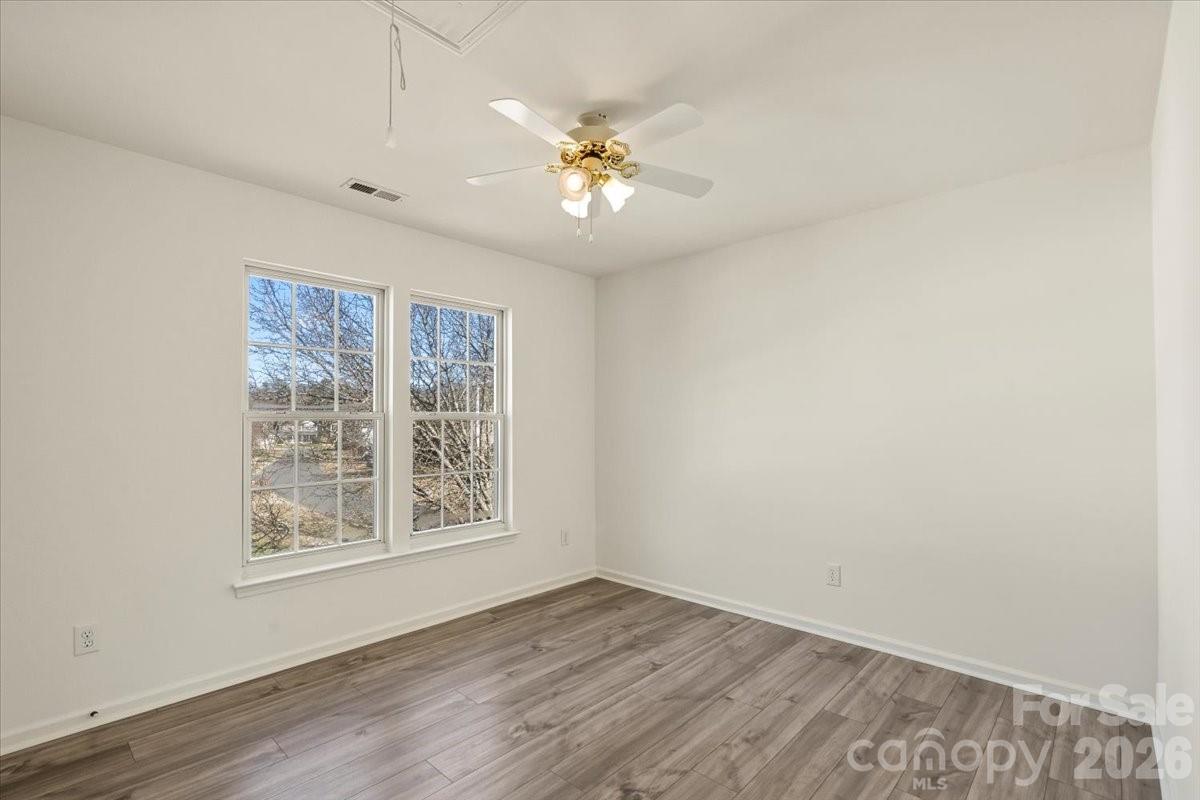 7215 Conifer Circle Indian Trail, NC 28079 - Photo 24 of 34 an empty room with wooden floor chandelier fan and windows
