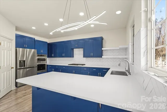 a kitchen with stainless steel appliances a sink a stove a refrigerator and cabinets
