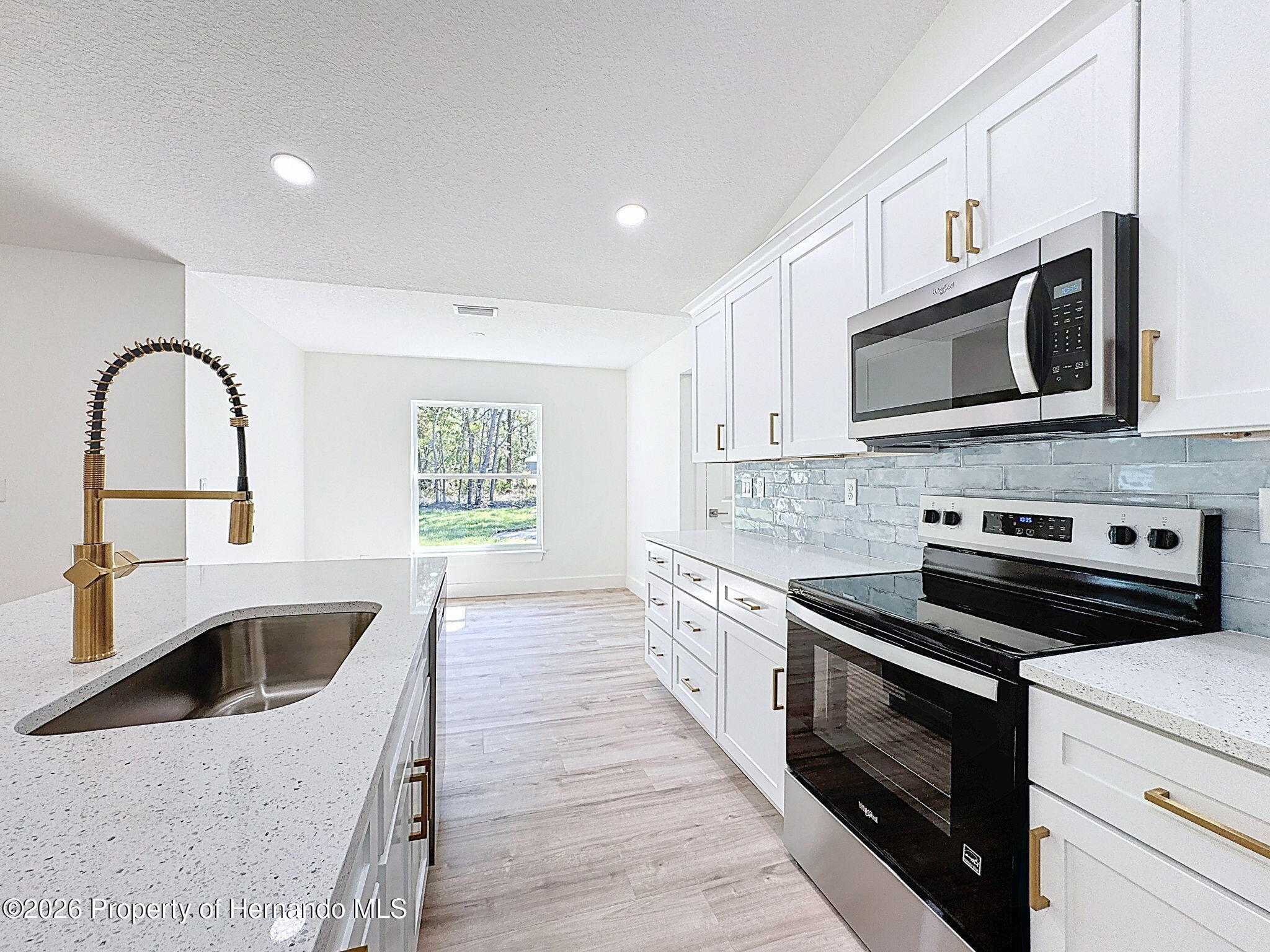 8988 Waterbird Way Weeki Wachee, FL 34613 - Photo 17 of 42 a kitchen with stainless steel appliances kitchen island a white stove top oven and sink