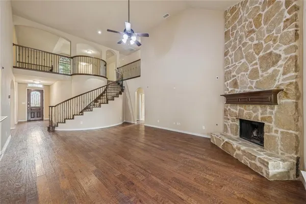 a view of an empty room with wooden floor fireplace and a window