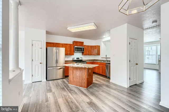 a kitchen with stainless steel appliances granite countertop a refrigerator a sink dishwasher a stove with wooden cabinets and floor