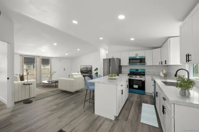 a large white kitchen with stainless steel appliances lots of counter space and wooden floor
