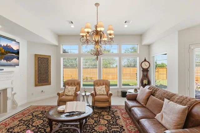 a living room with furniture a fireplace and a chandelier