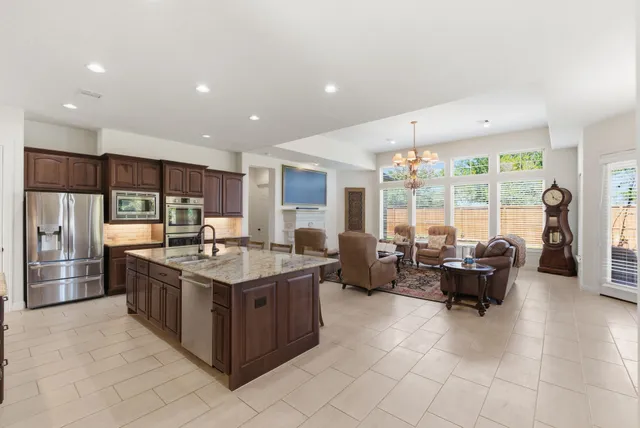 a kitchen with stainless steel appliances granite countertop a stove and a view of living room