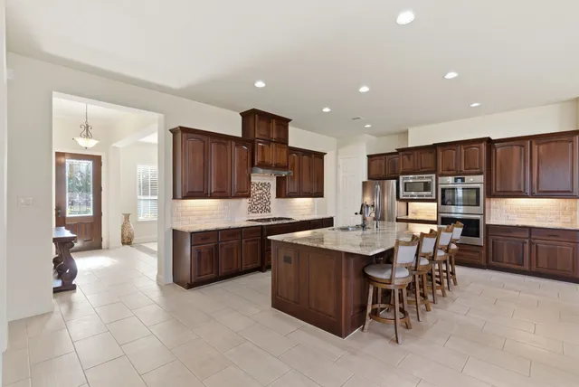a large kitchen with cabinets chairs and counter space