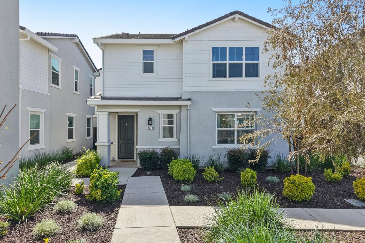2413 Seaside Road Lathrop, CA 95330 - Photo 1 of 37 a front view of a house with lots of flower plants