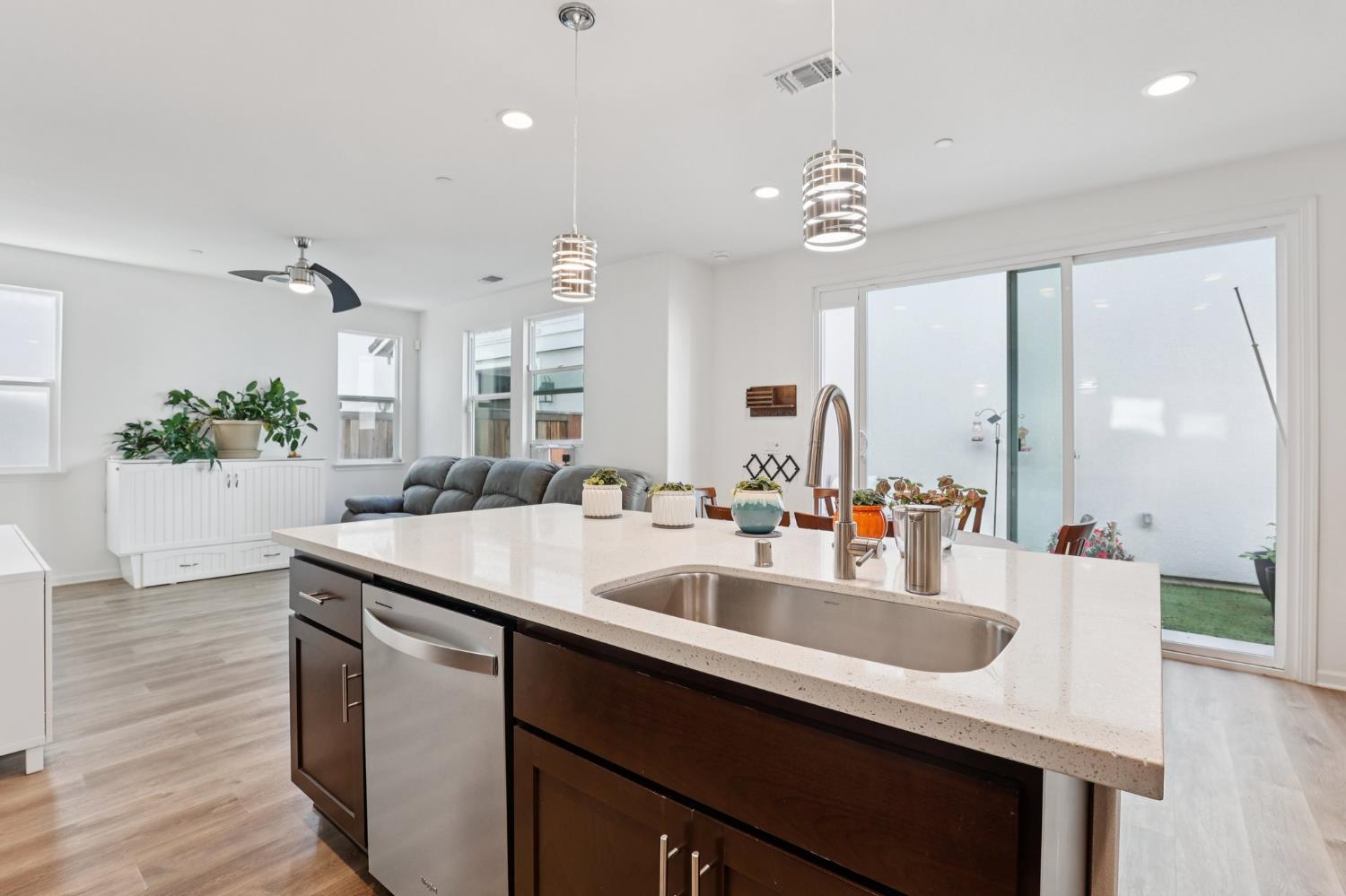 2413 Seaside Road Lathrop, CA 95330 - Photo 13 of 37 a kitchen with granite countertop a sink dishwasher a dining table and chairs with wooden floor