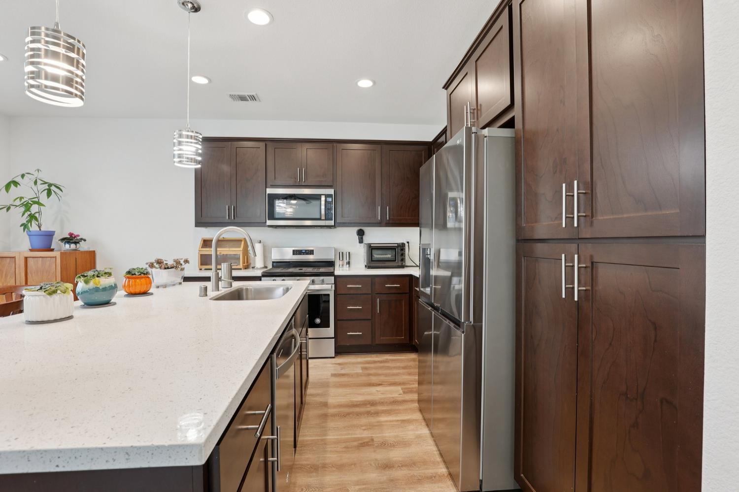2413 Seaside Road Lathrop, CA 95330 - Photo 10 of 37 a kitchen with kitchen island a counter top space a refrigerator and a sink