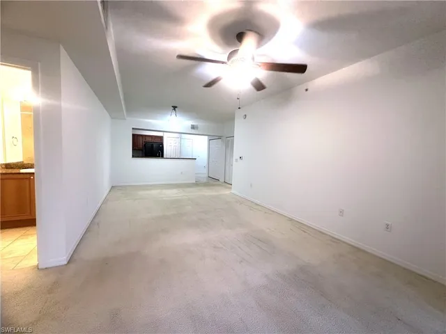 an empty room with ceiling fan and windows