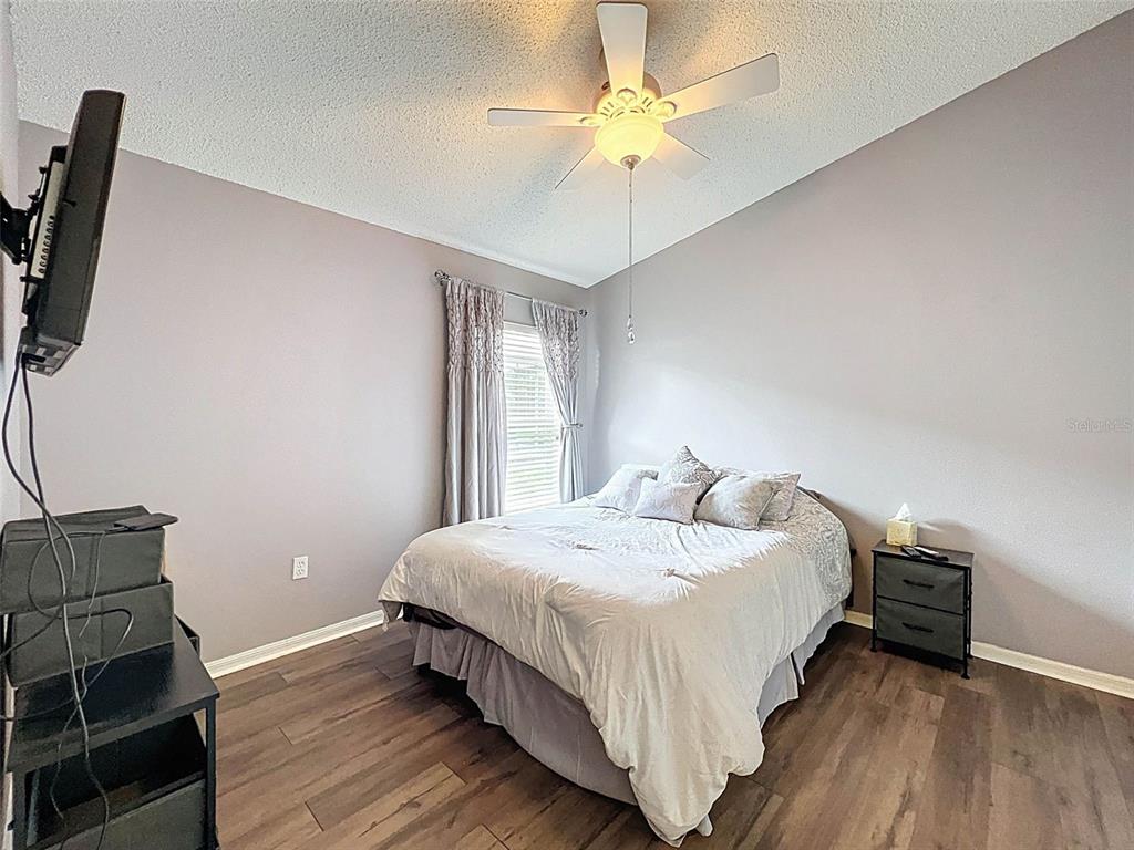 189 Center Oak Circle Spring Hill, FL 34609 - Photo 46 of 61 a bedroom with a bed a couch and a chandelier