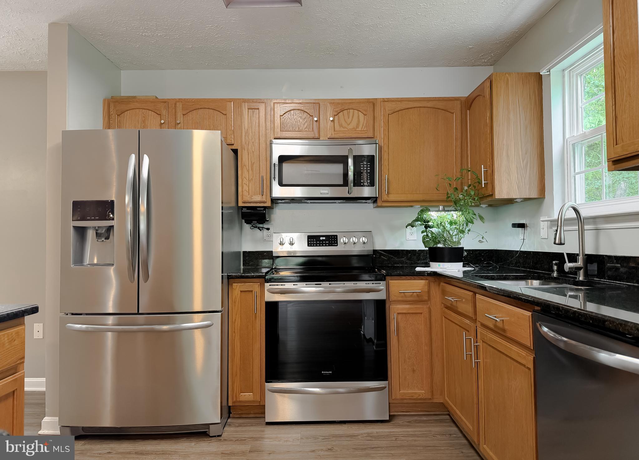 23801 McIntosh Road Hollywood, MD 20636 - Photo 4 of 35 a kitchen with granite countertop a refrigerator stove and microwave