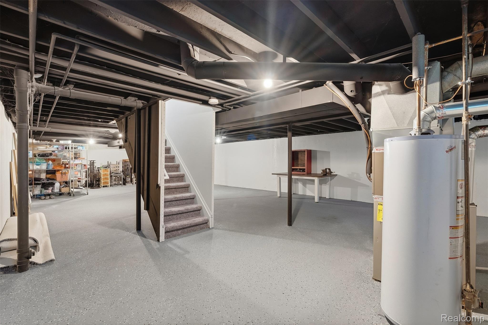 1750 Henbert Road West Bloomfield, MI 48324 - Photo 27 of 32 Finished basement space with exposed, painted ceiling joists, durable gray epoxy flooring, and a carpeted staircase